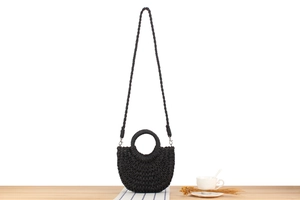 Detail of black woven crescent bag with circular handle and metal strap hooks