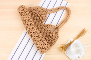 Flat lay of khaki woven tote bag on striped fabric with coffee cup for a summer holiday vibe