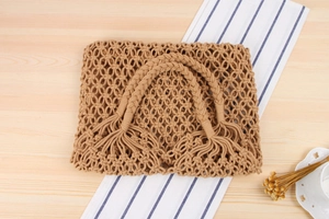Detail of handmade khaki macrame tote bag with woven knots and decorative tassels