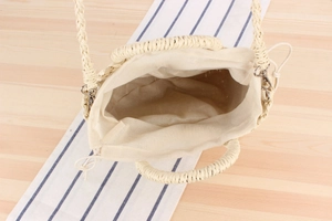 Detail view of woven handbag with canvas drawstring lining and metal buckles