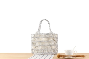 Vue détaillée d'un sac à main tissé argenté avec poignées rondes sur une table en bois