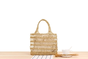 Détail du sac à main tissé doré avec pochette intérieure à cordon sur une table en bois