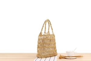 Détail du sac de plage tissé doré avec maille ajourée et doublure crème à cordon