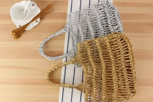 Détail de sacs de plage en maille tissée or et argent sur une surface en bois