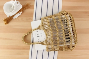 Détail d'un sac en filet tissé doré brillant posé sur une table en bois rustique