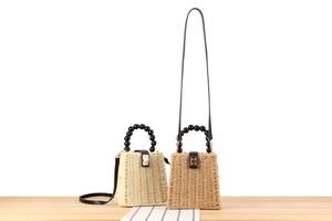 Détail du sac en paille tressée avec poignées en perles noires et fermoir métallique