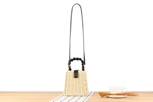 Détail du sac en paille tressée avec poignée à perles noires et fermoir doré rotatif