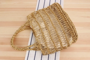Détail d'un sac de plage tissé doré avec motif en maille ajourée sur tissu rayé
