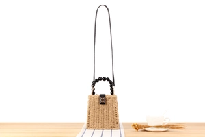 Détail du sac en paille tressée avec poignée en perles noires et fermoir métallique