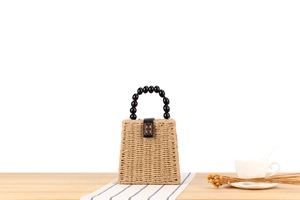 Détail du sac en paille tressée avec poignée en perles noires et fermoir doré
