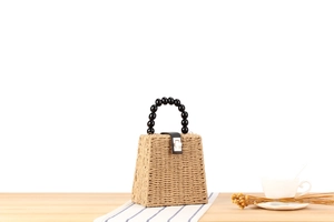 Détail d'un sac en paille tissée avec poignée à perles noires et fermoir en métal