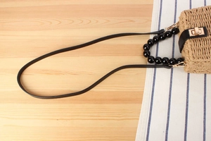 Détail d'un sac en paille avec poignée en perles noires et fermoir rotatif doré