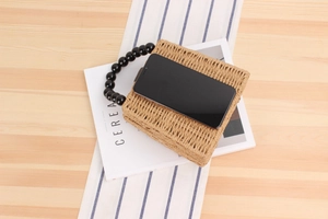 Détail du sac en paille avec anse en perles noires montrant sa capacité pour smartphone
