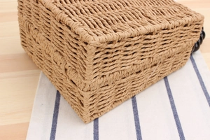 Gros plan sur la texture en paille tressée et la perle noire d'un sac de plage carré