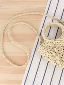 Minimalist hand-woven straw crossbody bag with round handle for beach vacations