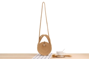 Detail of round woven cotton rope bag with wooden button closure on wooden table
