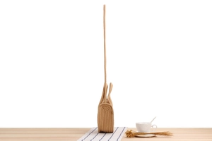 Side view of khaki woven cotton rope crossbody bag with top handle on white surface