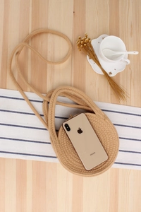 Detail of round woven cotton rope crossbody bag with smartphone for size reference
