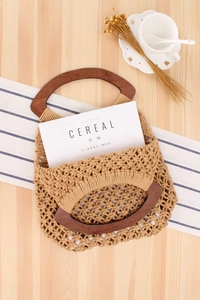 Detail of hand-woven cotton mesh beach bag with round wooden handle and magazine inside