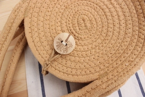 Detailed close-up of a round woven cotton rope bag featuring a laser-engraved wooden button