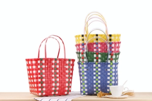 Detail view of colorful woven basket bags with plaid patterns and clear tube handles