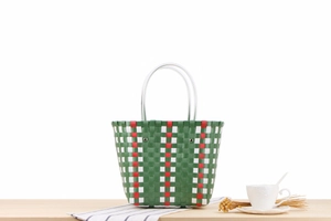 Detailed view of colorful woven beach bag with green, white, red patterns and round handles