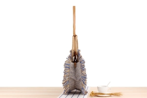 Detail of paper straw woven tote bag with blue tassels and faux leather strap