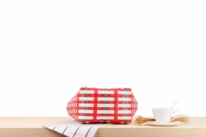 Close-up of red and white checkered woven basket bag with green stripes on a wooden table