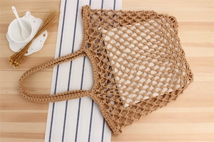 Gros plan d'un sac en filet tissé à la main avec doublure en toile sur table en bois