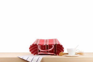 Detail of red plaid woven beach bag with colorful stripes and pink plastic handles