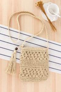 Detail of handmade woven straw bag with hollow floral pattern and beaded tassels