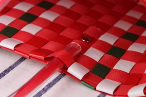 Macro detail of red, white and green woven plaid pattern with metal clasp and clear handle