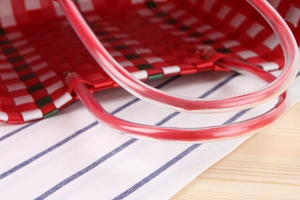 Detail of red and white checkered woven bag showing clear plastic handles and craftsmanship