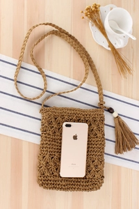 Detail of bohemian hand-woven bag with hollow star patterns and tassel bead accent