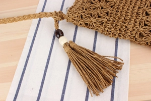 Detail of crochet floral pattern with tassel and wooden beads on straw bag