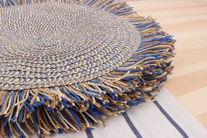 Detail view of woven paper rope tote bag texture with decorative fringe and tassels