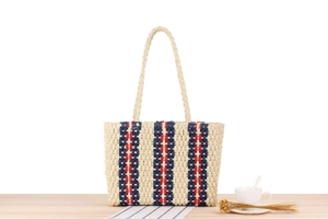 Detailed texture of vertical navy and red stripes on beige woven straw tote bag