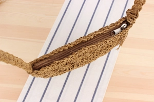 Detailed close-up of woven shoulder bag with smooth metal zipper and handmade texture