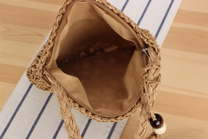 Detail of woven straw bag with zipper closure, fabric lining and decorative wooden beads