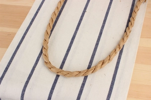 Close-up of durable brown hand-woven paper rope handles on a natural woven beach bag