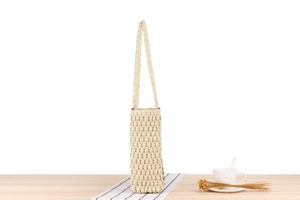 Detailed side view of beige paper rope woven shoulder bag with striped accent detail