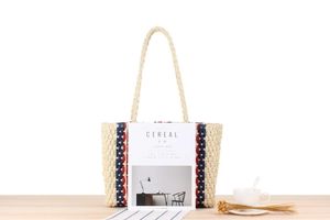 Detailed view of summer paper straw tote bag with vertical stripes on a wooden table