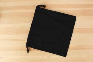 Detail of a black canvas drawstring inner bag on a light wooden background