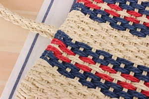 Detailed close-up of woven straw handbag showing striped texture and handle connection