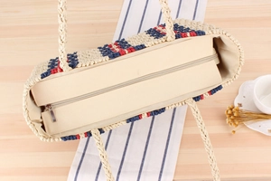 Close-up of striped paper rope woven beach bag with secure metal zipper closure