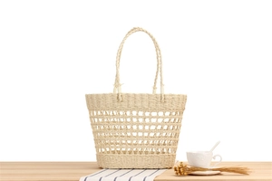 Close-up of hand-woven paper rope tote bag featuring hollow mesh pattern and long handles