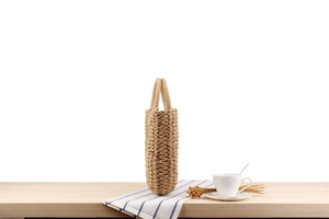 Detail of hand-woven straw tote bag with round handles on a rustic wooden table