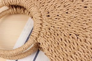 Detailed view of handmade straw woven tote bag with integrated circular handles and texture