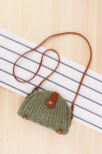 Detailed macro view of sage green woven paper straw bag with brown leather accents