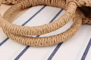Detail shot of sturdy double round handles on the handmade straw woven beach handbag